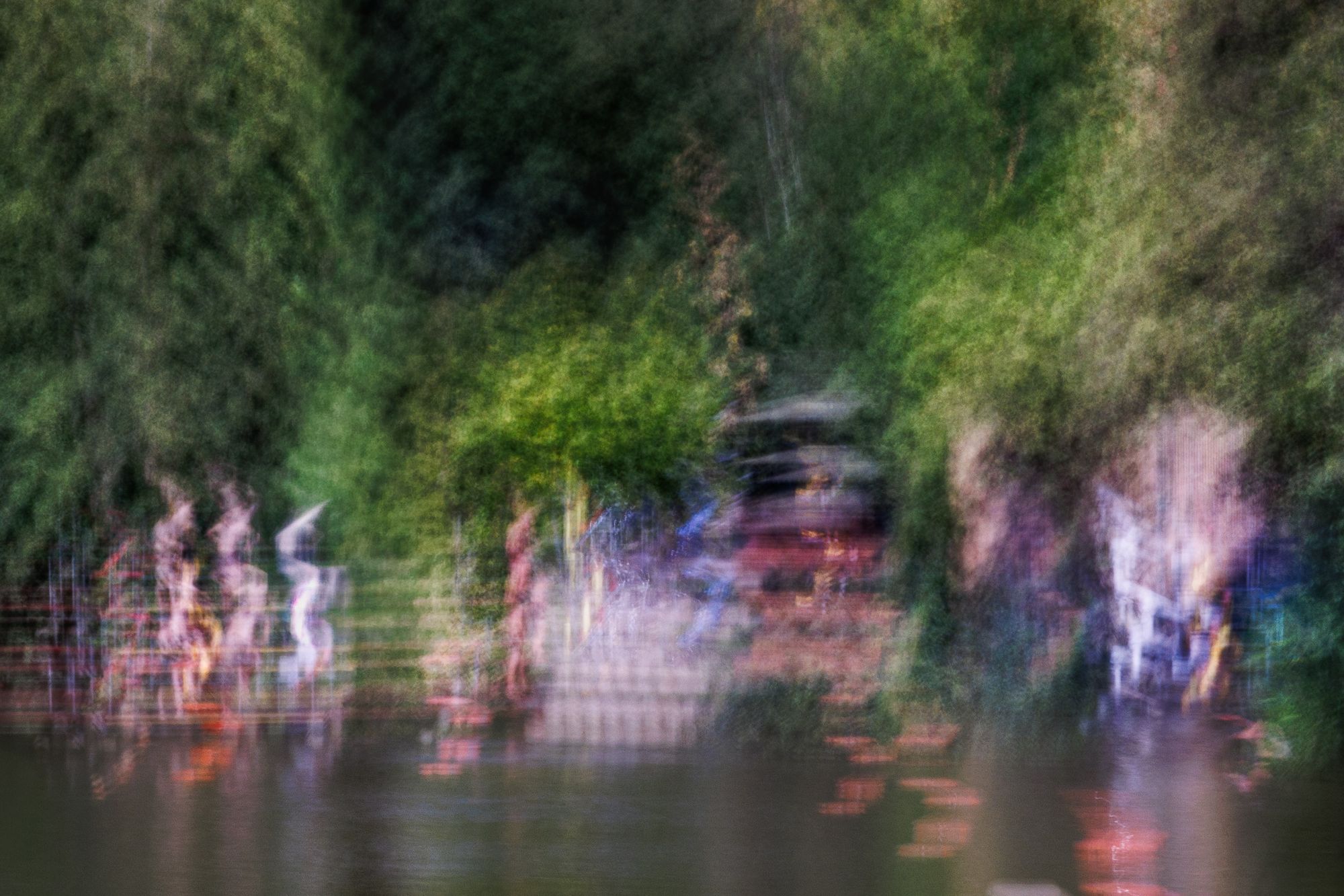 Figures streaking past a green hedge and railings